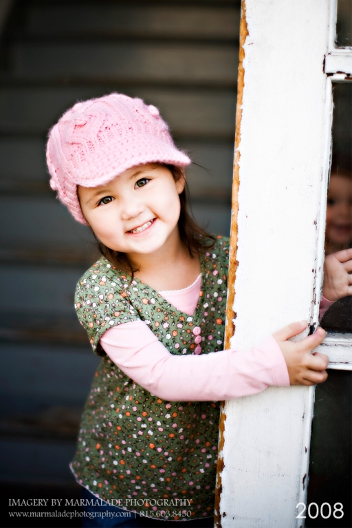 Little girl with a pink hat photographed in a doorway