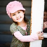 Little girl with a pink hat photographed in a doorway
