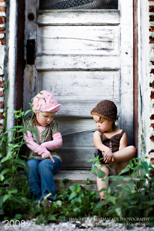 Two young sisters sitting in an old rustic doorway