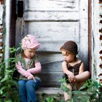 Two young sisters sitting in an old rustic doorway