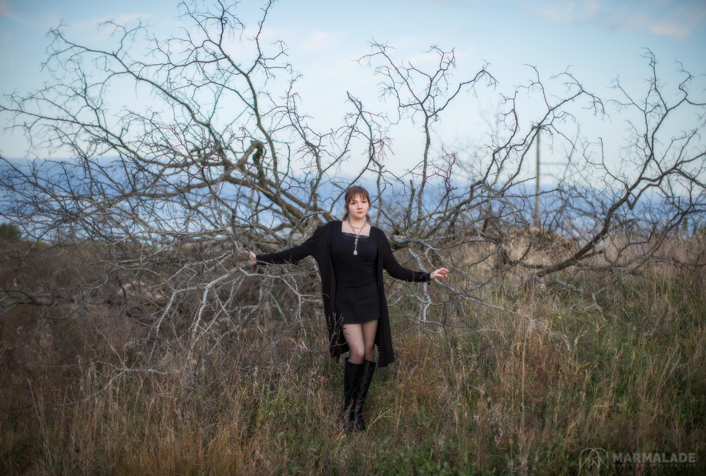 Photo of a young woman in a natural setting with a felled tree that resemble angel wings