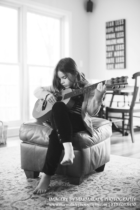 A photo of a girl playing her guitar in her Naperville home