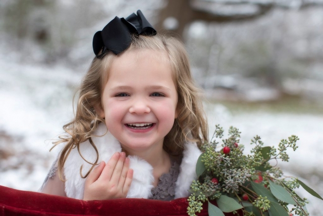 Snow day photo with a preschool aged girl laughing and having fun while being photographed