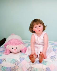 A cute toddler sits on her bed at home in Oak Park, photo on location by Marmalade Photography